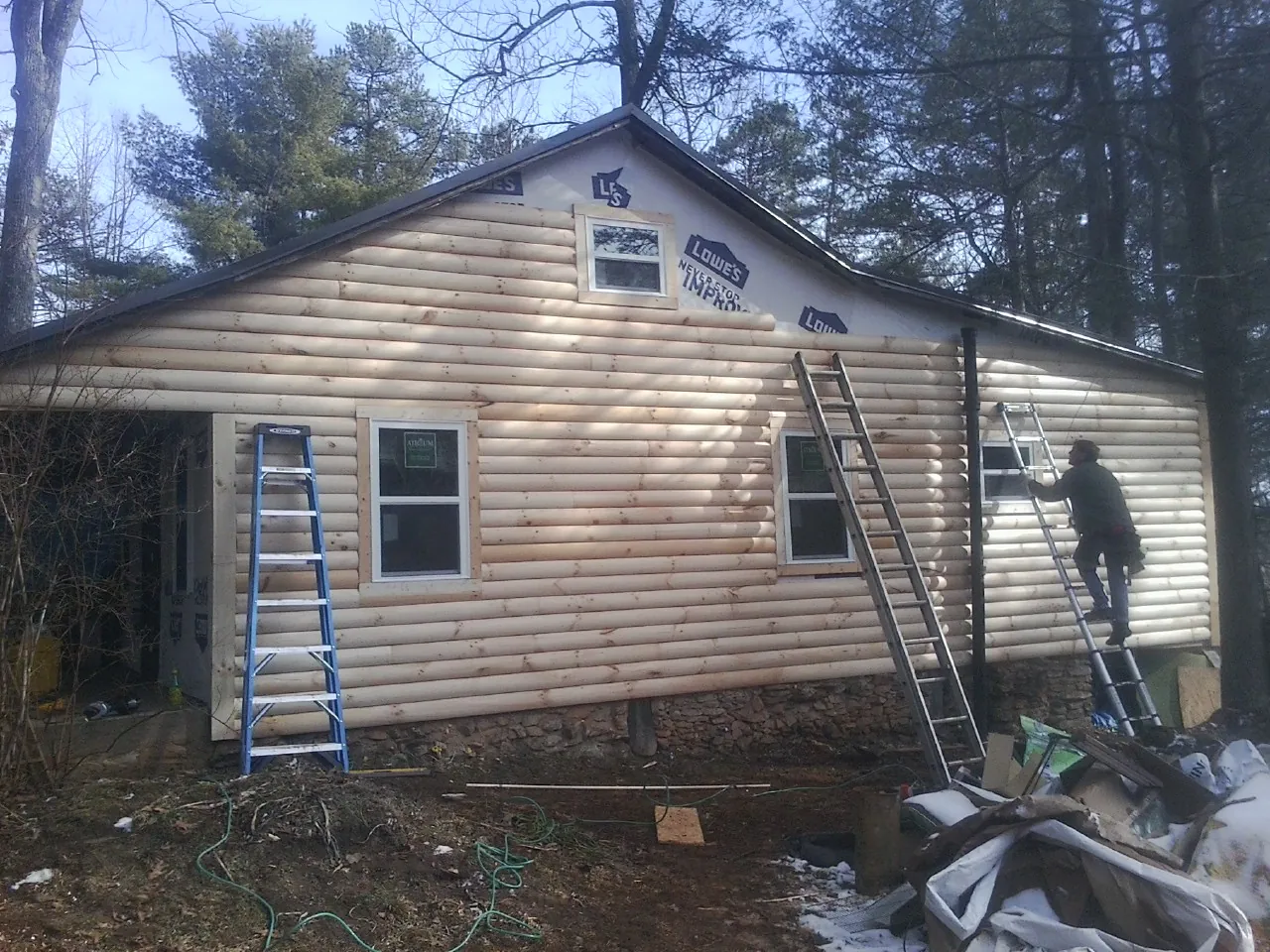 Ladders set against fresh log siding during an exterior remodel in Highfalls