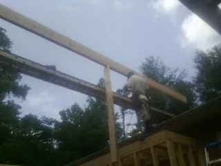 Carpenter setting a ridge beam over a new addition frame — Ice Dam Removal by Roofing Brothers in Highfalls