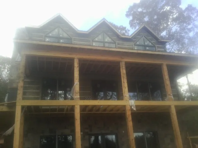 Dormers and porch framing on a large log home under construction — Roof Coating work by our crew in Highfalls