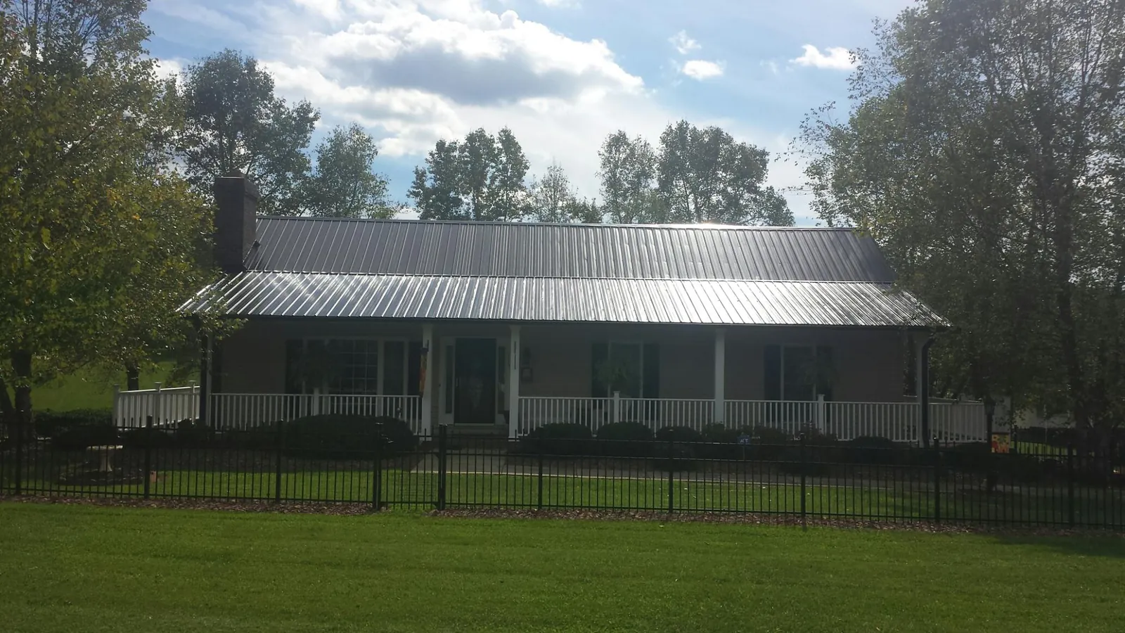 Gray metal roof on a brick ranch with a full width front porch — Gutter Guard Installation work by our crew in Highfalls