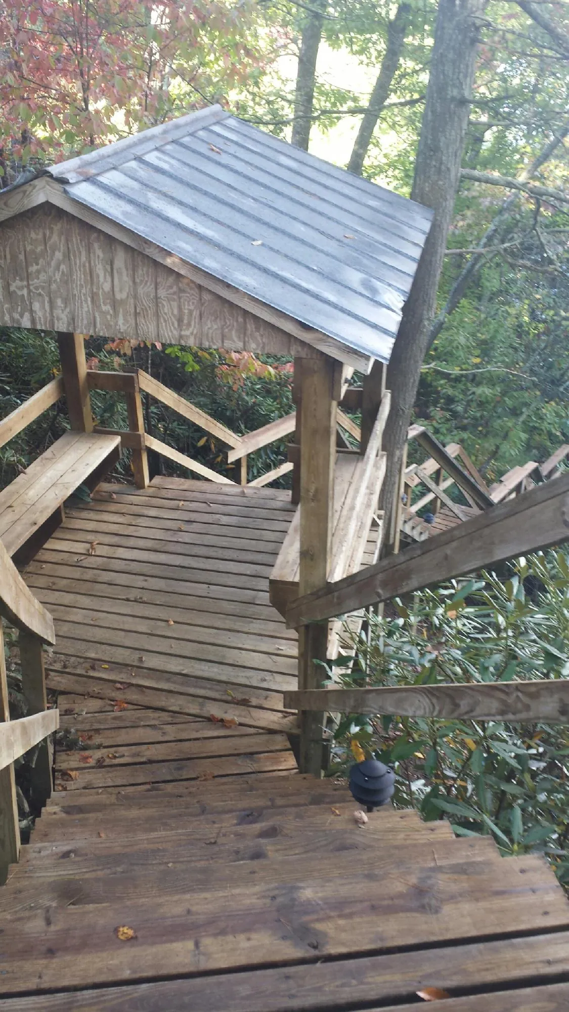Metal roofed shelter over wooden steps on a wooded walkway — Skylight Repair & Installation work by our crew in Highfalls