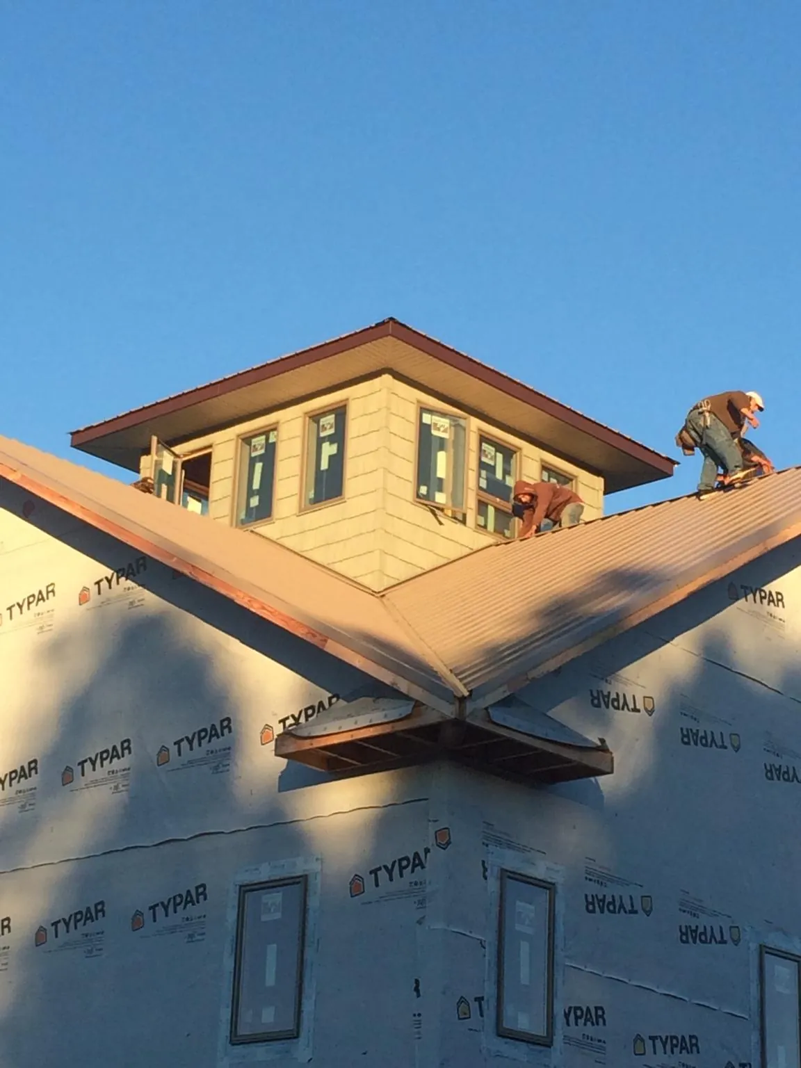 Roofers working around a rooftop cupola on a new metal roof at sunset — Roof Waterproofing in Highfalls by Roofing Brothers